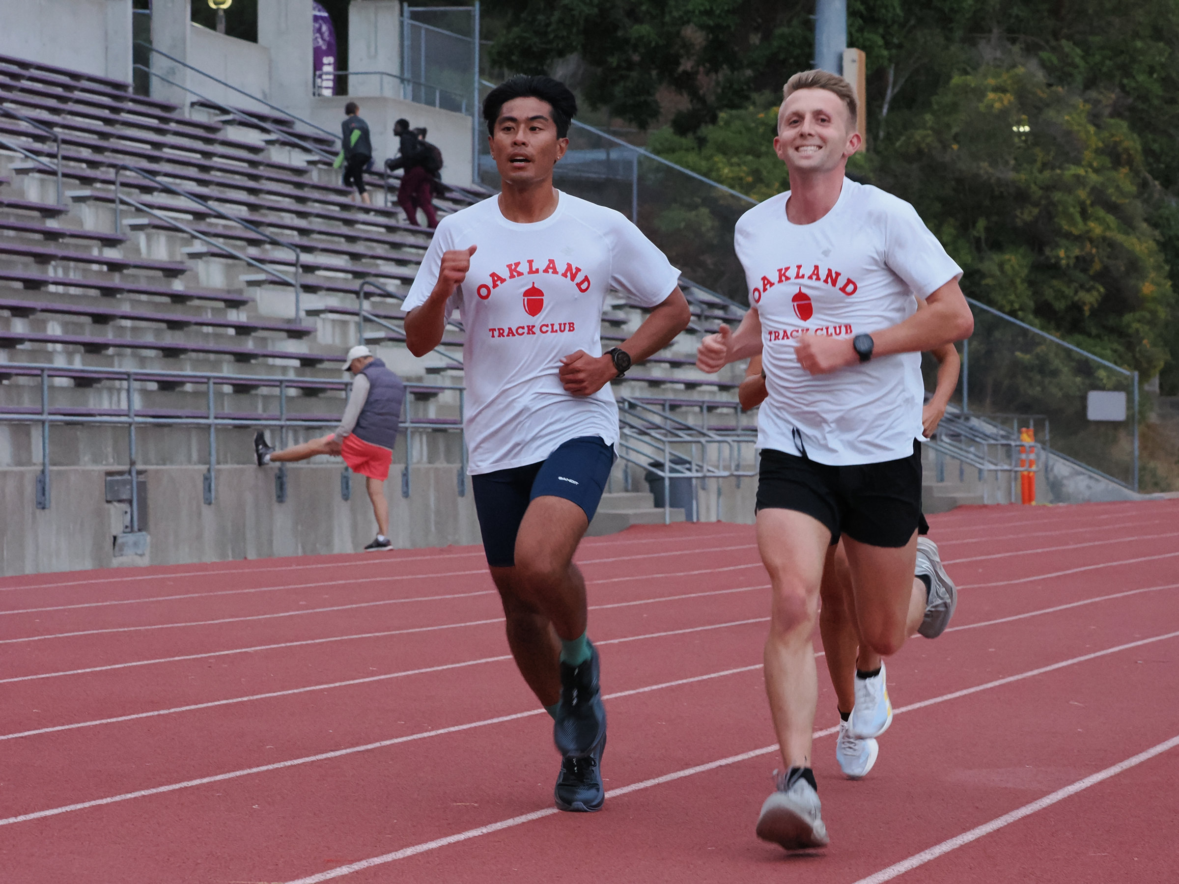 Two Oakland Track Club runners racing on a track